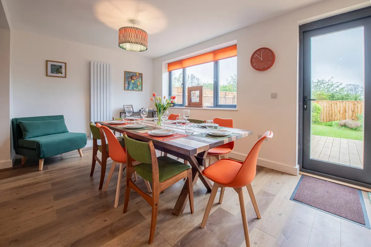 Bright modern dining area with colourful chairs and garden views